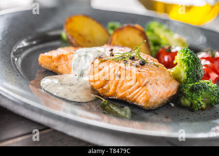 Gebratenes Lachsfilet broccoli Tomaten und Bratkartoffeln mit Dill Sauce Stockfoto