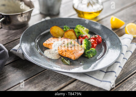 Gebratenes Lachsfilet broccoli Tomaten und Bratkartoffeln mit Dill Sauce Stockfoto