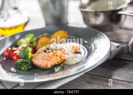 Gebratenes Lachsfilet broccoli Tomaten und Bratkartoffeln mit Dill Sauce Stockfoto