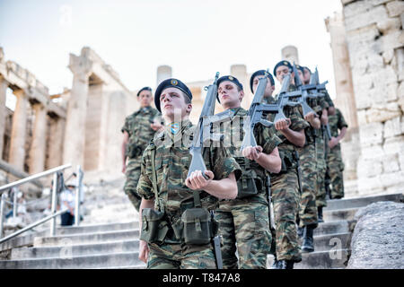 Akropolis UNESCO-Weltkulturerbe griechische Soldaten marschieren Athen Griechenland / ATHEN, Griechenland – griechische Soldaten marschieren in Formation an der Akropolis, einem UNESCO-Weltkulturerbe, das die Skyline von Athen dominiert. Das Parthenon mit seinen berühmten dorischen Säulen und Giebeln bildet das Herzstück dieser alten Zitadelle. Andere klassische Bauten auf dem felsigen Hügel sind das Erechtheion und der Tempel der Athena Nike, die alle aus dem 5. Jahrhundert v. Chr. stammen und als beständige Beispiele der antiken griechischen Zivilisation und Architektur gelten. Stockfoto