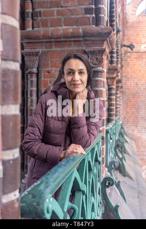 Frau lehnte sich gegen Geländer der alten Gebäude Stockfoto