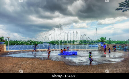 Grand Cayman, Cayman Islands, Aug 2018, Kinder spielen an einem Brunnen auf einem platz der Camana Bay, einer modernen Hafenstadt in der Karibik Stockfoto