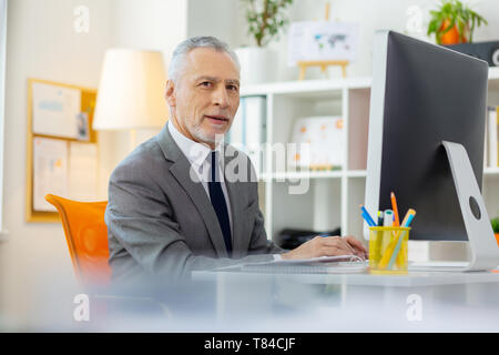 Neugierig kurzhaarige Geschäftsmann allein im Büro Stockfoto