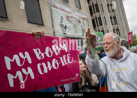 Ein anti-Abtreibung Christian Wellen seinen heiligen Rosenkranz an die Rechte der Frauen pro-choice-Unterstützer wie die Gruppen Zusammentreffen im März für Life UK protestieren. Stockfoto