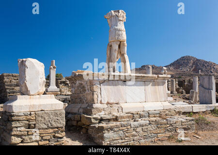 Delos, Mykonos, südliche Ägäis, Griechenland. Kopflose Statue steht man inmitten archäologische Überreste, Berg Kynthos im Hintergrund. Stockfoto