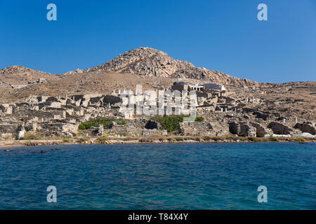 Delos, Mykonos, südliche Ägäis, Griechenland. Blick vom Meer auf die Delos archäologische Stätte an den unteren Hängen des Berg Kynthos. Stockfoto