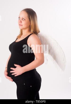 Studio Portrait von eine schöne junge schwangere Frau mit weißer Engel Flügel Stockfoto