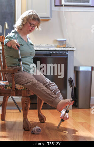 Frau mit TAR-Syndrom sie ihr Haar Bürste mit ihren Füßen Stockfoto