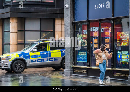 Leicester Square, London, Großbritannien, 8. Februar 2019 - Eine Frau geht vor Casino, Polizei Auto geparkt Stockfoto