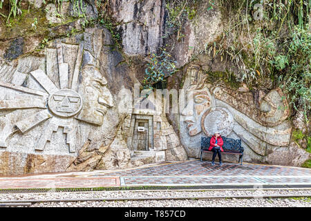 Aguas Caliente - April 8, 2019: Frau sitzt auf der Bank und skulpturalen Kunst auf dem Felsen die Inkas kulturelle Identität von den Künstlern geschnitzt, Aguas Cal Stockfoto