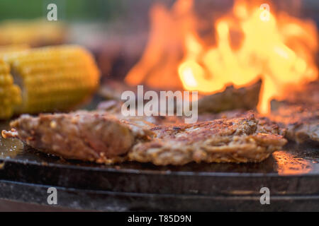 Frisches rohes Steak mit Mais ein offenes Feuer Grill Stockfoto