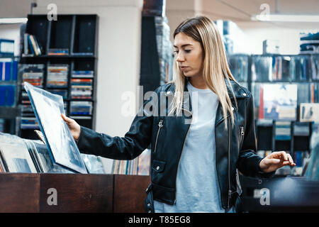 Junge attraktive Frau Wahl Schallplatte in der Musik Record Shop. Melomaniac oder Musik süchtiger Konzept. Stockfoto