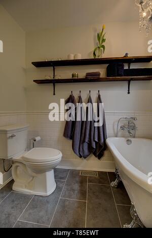 Aktualisiert Badezimmer mit Fliesen im Subway-Stil, frei stehender Badewanne, vintage Holz Regale. Moderne Wohnkultur. Stockfoto