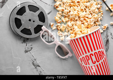 Komposition mit lecker Popcorn und Filmrolle auf hellen Hintergrund Stockfoto