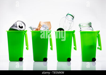 Reihe der Grünen Papierkörbe mit Flasche und Dose auf reflektierenden Hintergrund Stockfoto