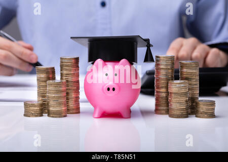 In der Nähe von Piggy Bank tragen Staffelung hat und gestapelte Münzen Vor Unternehmer Stockfoto