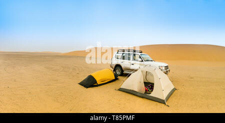 Camping in der sudanesischen Wüste mit zwei kleinen Zelten, einem Off-Road-Fahrzeug und eine Sanddüne im Hintergrund, Panorama. Stockfoto