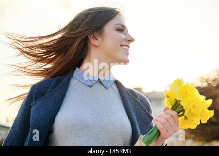 Outdoor Portrait der jungen schönen Mädchen mit Blumenstrauß aus gelben Frühlingsblumen. Stockfoto