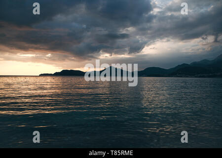 Schöne Aussicht auf den Sonnenuntergang und die natürliche Landschaft mit dem Meer und den Hügeln oder Bergen in Montenegro im Sommer. Stockfoto