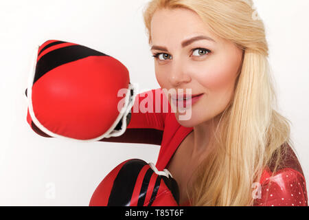 Portrait der junge lächelnde Frau in Boxhandschuhen auf grauem Hintergrund posiert Stockfoto