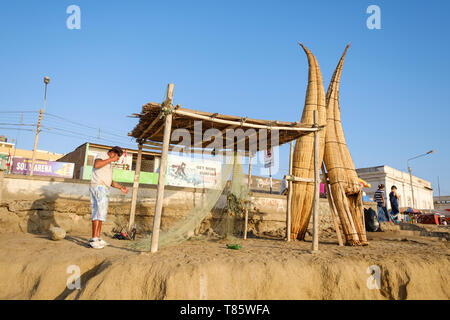 Fischer zur Festsetzung Netze Neben caballitos de Totora (traditionelle Boote aus Schilf und zum Angeln und Surfen) auf Cusco, Peru am Strand Stockfoto