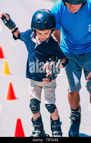 Großvater lehre Enkel zu Roller Skate Stockfoto