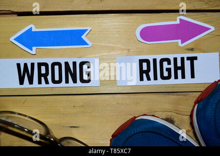 Richtig oder Falsch entgegengesetzte Richtung Schilder mit Turnschuhen und Brillen auf Holz vintage Hintergrund. Wirtschaft und Bildung Konzepte Stockfoto