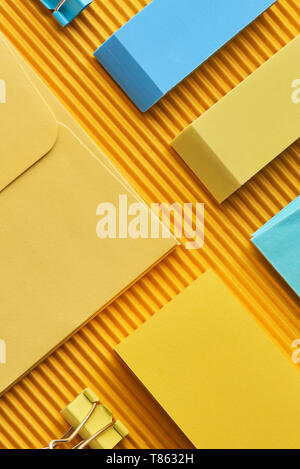 Blick von oben auf die Haftnotizen, Umschlag und Radiergummis auf Gelb Stockfoto
