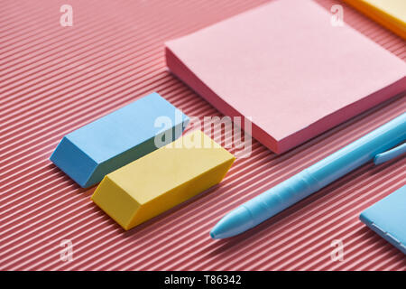 Nahaufnahme der Haftnotizen, Radiergummis und Stift auf Rosa Stockfoto