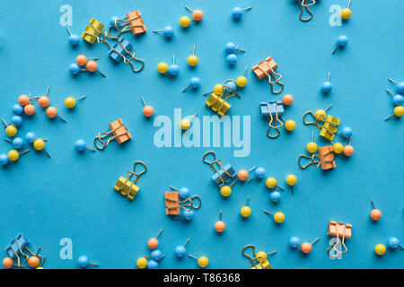 Blick von oben auf die bunten verstreut push Pins und Büroklammern isoliert auf Blau Stockfoto