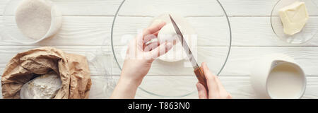 Panorama-aufnahme der Frau mit Messer cracking Egg in der Schüssel beim Kochen am Tisch Stockfoto