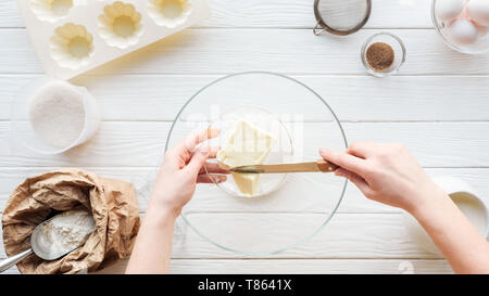 7/8-Ansicht von Frau schneiden Butter in der Schüssel auf dem Tisch mit den Zutaten Stockfoto