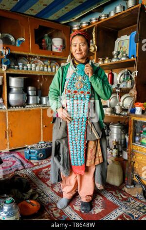 Indien, Bundesstaat Jammu und Kashmir, Himalaya, Ladakh, Zanskar, Photoksar, Frau zeigen ein Perak in ihrer Küche, eine lange traditionelle Kopfbedeckung dekoriert mit großen Türkisen, rote Koralle Perlen, polierte Bernstein, Amulette oder talismane in Silber und Gold Stockfoto