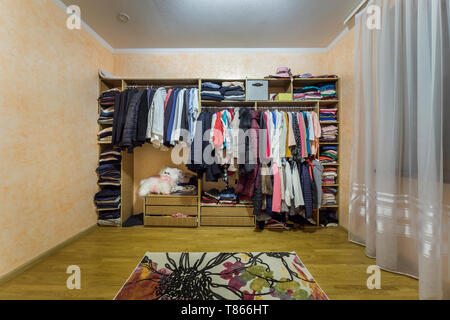 Öffnen dressing Schrank Kleiderschrank voll von verschiedenen männlichen und weiblichen bunte Kleidung und Zubehör auf Kleiderbügeln und Regal. Moderne Möbel, komfortable h Stockfoto