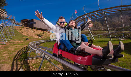 Aufgeregt, junges Paar fahren Alpine Coaster und genießen Sie schöne sonnige Tag in der Natur Stockfoto