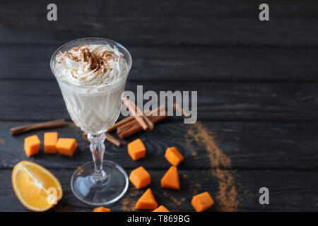 Glas Latte mit Zimt und Kürbis auf hölzernen Tisch Stockfoto