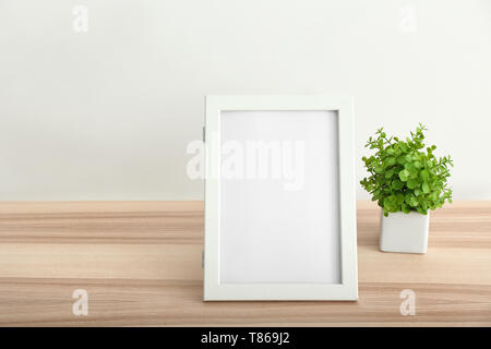 Leeren Bilderrahmen und zimmerpflanze auf Tisch gegen weiße Wand Stockfoto