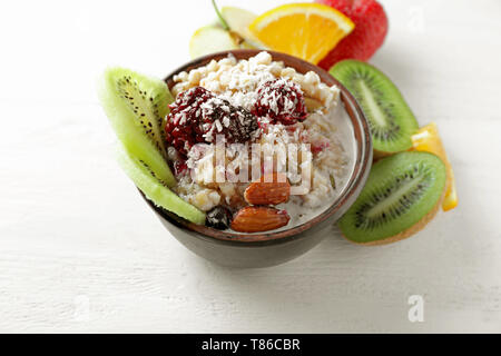 Schüssel mit leckeren Haferbrei, Beeren und Früchte auf hellen Hintergrund Stockfoto