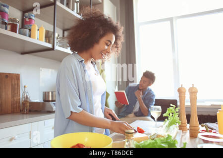 Junge Afrikaner - Frau kochen Essen und ihr Freund lesen Rezeptbuch in der Küche Stockfoto