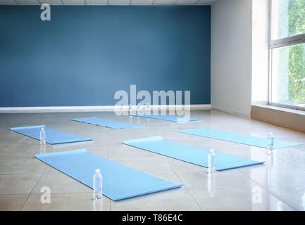 Yogamatten, Wasser in Flaschen auf dem Boden in der Turnhalle Stockfoto