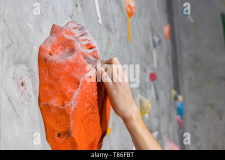 Hand des weißen Mannes hält an der Kletterwand Stockfoto