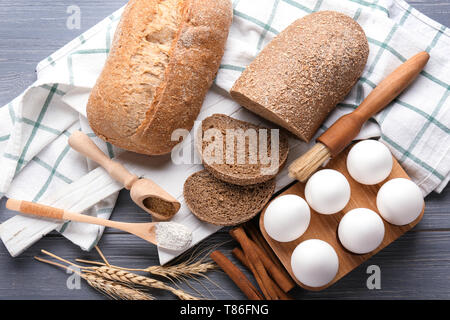 Zusammensetzung mit frischem Brot und Zutaten für die Zubereitung von Gebäck auf Holz- Hintergrund Stockfoto