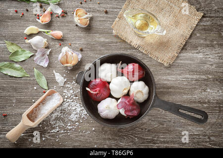 Zusammensetzung mit roten Zwiebeln, Knoblauch und Gewürzen auf Holz- Hintergrund Stockfoto