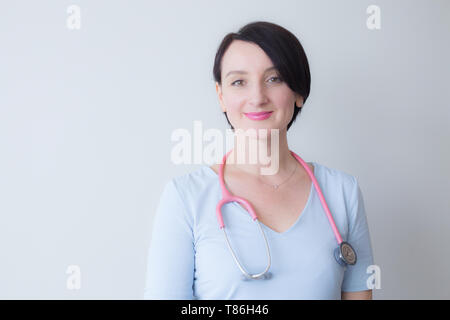 Attraktive Arzt Frau Rosa Stethoskop lächelnd Stockfoto