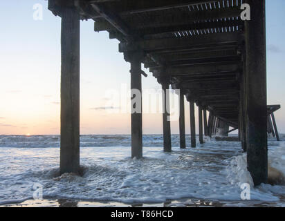 Sonnenaufgang am Claremont Pier mit Wellen über den super-Struktur brechen, Lowestoft Stockfoto