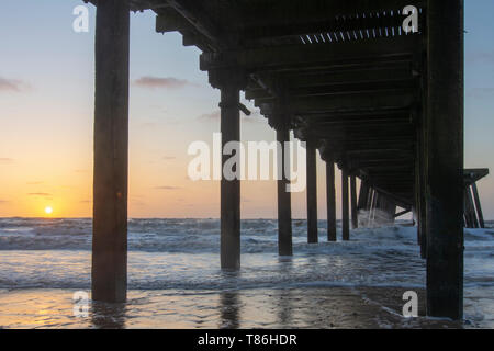 Sonnenaufgang am Claremont Pier mit Wellen über den super-Struktur brechen, Lowestoft Stockfoto