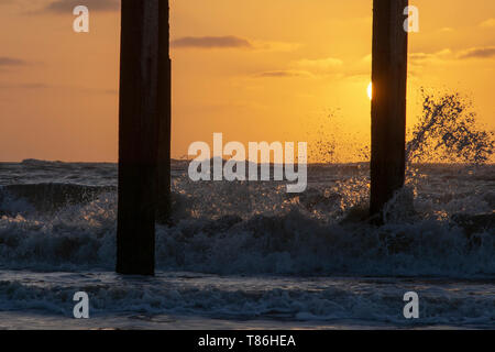 Sonnenaufgang am Claremont Pier mit Wellen über den super-Struktur brechen, Lowestoft Stockfoto