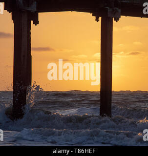 Sonnenaufgang am Claremont Pier mit Wellen über den super-Struktur brechen, Lowestoft Stockfoto