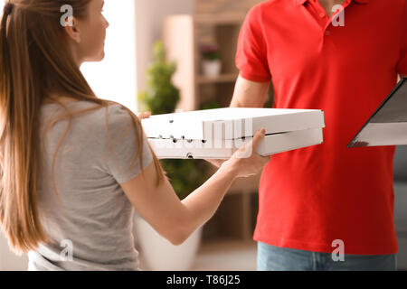 Junger Mann, Pizzakartons, Frau zuhause. Food Delivery Service Stockfoto