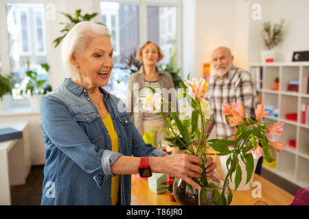 Gerne fröhliche Frau Blumen in der Vase berühren. Stockfoto